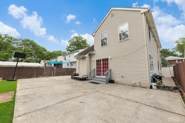 rear view of house featuring entry steps, a patio area, and fence