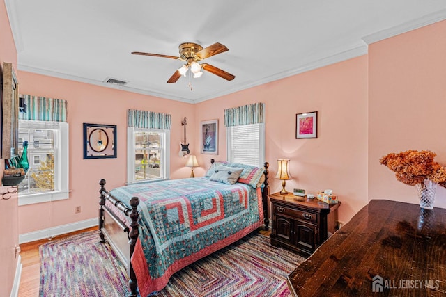 bedroom featuring wood finished floors, crown molding, baseboards, and a ceiling fan
