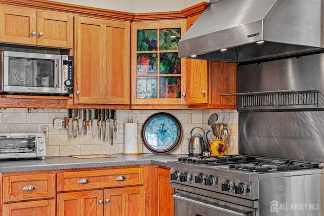 kitchen with appliances with stainless steel finishes, ventilation hood, backsplash, and brown cabinets