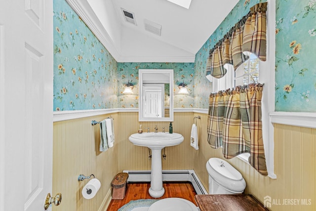bathroom featuring lofted ceiling, wainscoting, toilet, wood finished floors, and wallpapered walls