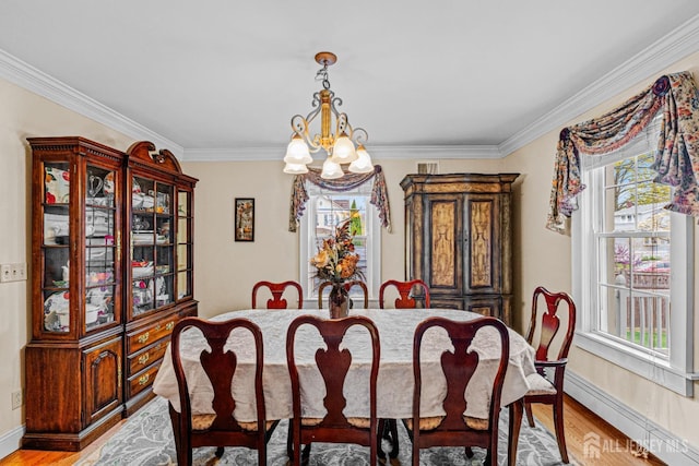 dining area with a chandelier, crown molding, light wood-style flooring, and baseboards