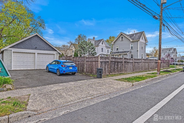 view of side of home featuring a residential view, a detached garage, and fence