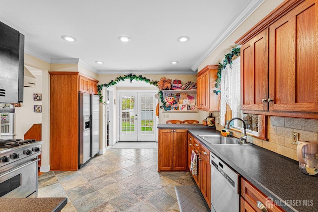kitchen featuring appliances with stainless steel finishes, a sink, crown molding, stone tile flooring, and dark countertops