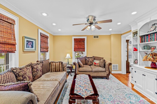 living room featuring plenty of natural light, light wood-style flooring, a ceiling fan, recessed lighting, and ornamental molding