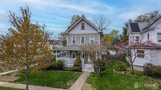 victorian house featuring covered porch, a front yard, and solar panels
