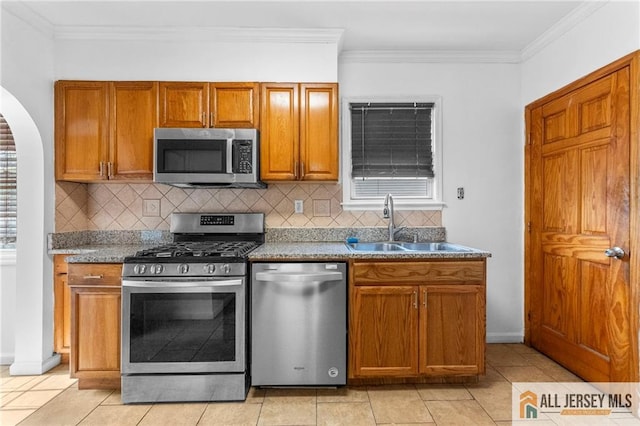 74 Charles St, Carteret, NJ 07008 - kitchen with appliances with stainless steel finishes, a sink, arched walkways, backsplash, and brown cabinets