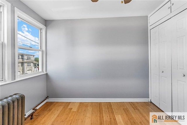 74 Charles St, Carteret, NJ 07008 - unfurnished bedroom featuring radiator heating unit, a closet, light wood-type flooring, baseboards, and a ceiling fan