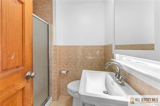 74 Charles St, Carteret, NJ 07008 - bathroom with tile walls, a shower stall, a sink, toilet, and tile patterned flooring