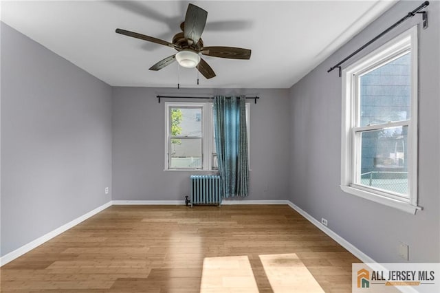 74 Charles St, Carteret, NJ 07008 - spare room featuring radiator heating unit, light wood-style flooring, ceiling fan, and baseboards