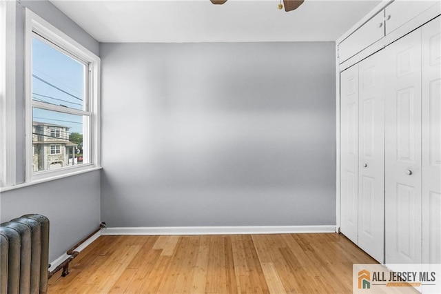 74 Charles St, Carteret, NJ 07008 - unfurnished bedroom with radiator, baseboards, a closet, and light wood-style flooring