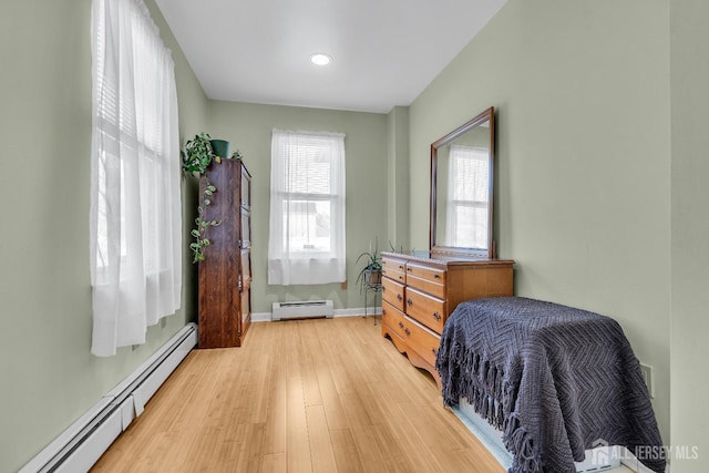 bedroom featuring a baseboard heating unit and light hardwood / wood-style flooring