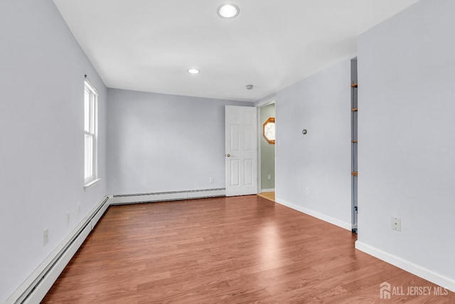 spare room with a baseboard radiator and light wood-type flooring