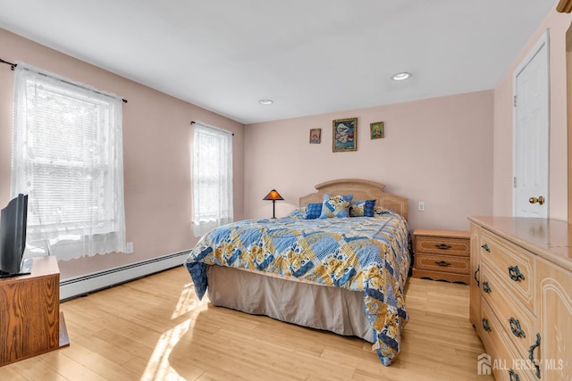 bedroom with a baseboard heating unit and light hardwood / wood-style flooring