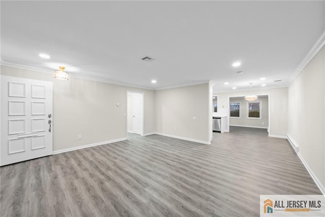 unfurnished living room featuring wood-type flooring, an inviting chandelier, and crown molding