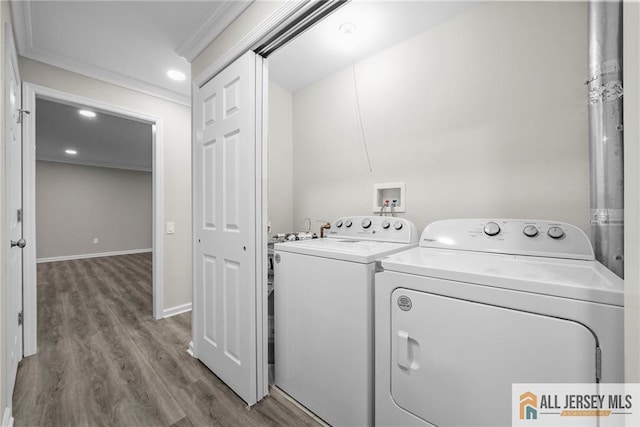 clothes washing area with crown molding, wood finished floors, laundry area, and washing machine and clothes dryer