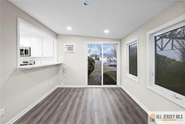 dining room featuring recessed lighting, wood finished floors, baseboards, and a wall mounted air conditioner