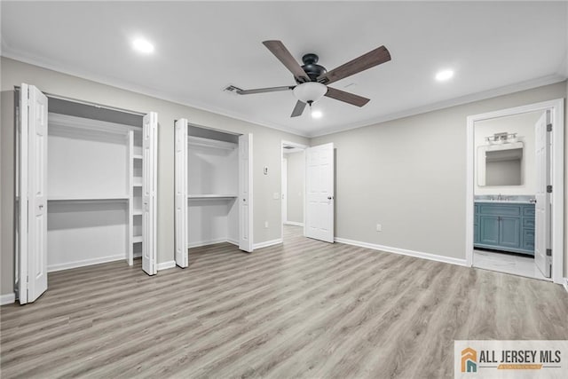 unfurnished bedroom featuring light wood finished floors, crown molding, baseboards, multiple closets, and a sink