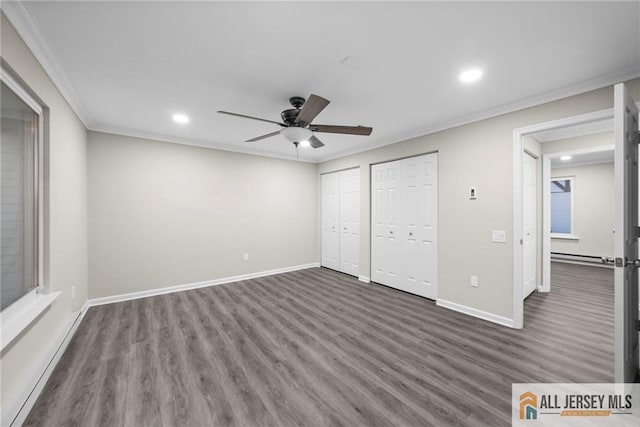 unfurnished bedroom with ceiling fan, dark wood-type flooring, ornamental molding, and multiple closets