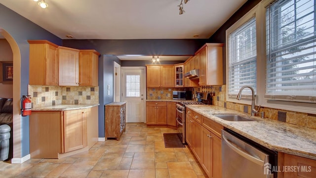 kitchen with light stone counters, sink, tasteful backsplash, and stainless steel appliances