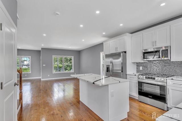 65 Bayview St, Aberdeen, NJ 07721 - kitchen featuring stainless steel appliances, decorative backsplash, a kitchen island, open floor plan, and white cabinetry