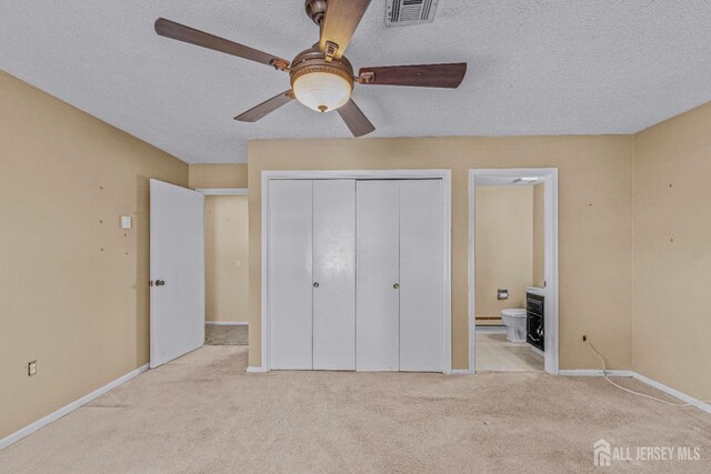 unfurnished bedroom with ensuite bath, ceiling fan, light colored carpet, a textured ceiling, and a closet