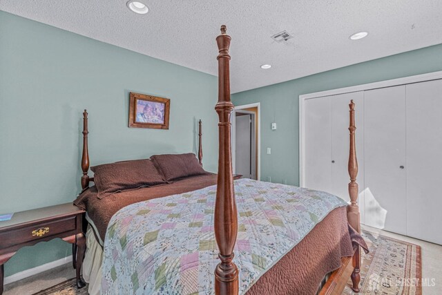 carpeted bedroom with a textured ceiling and a closet