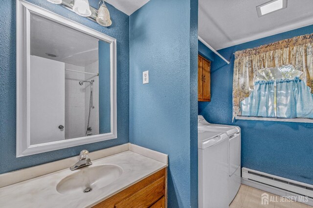 bathroom with vanity, independent washer and dryer, walk in shower, and a baseboard heating unit