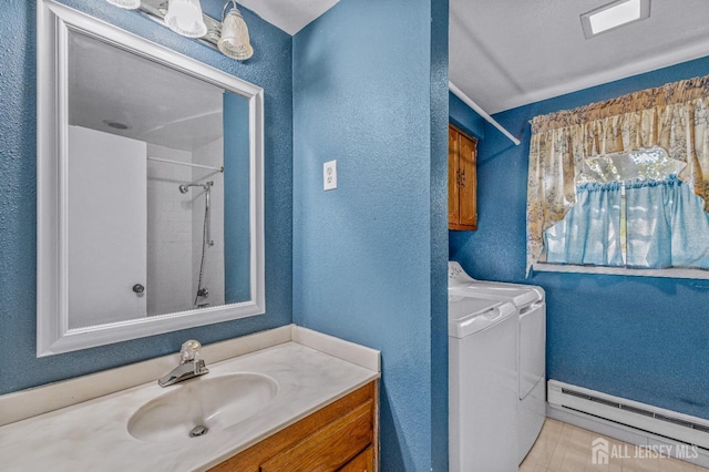 full bathroom with a textured wall, vanity, a baseboard heating unit, and washing machine and clothes dryer