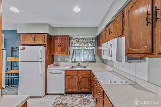 kitchen with light countertops, white appliances, a sink, and brown cabinets