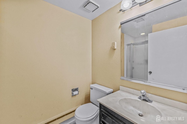 bathroom with toilet, a shower with door, baseboards, and vanity