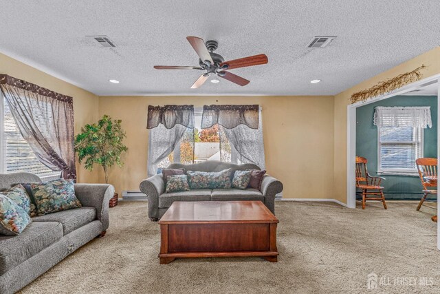 carpeted living room featuring ceiling fan, a textured ceiling, a wealth of natural light, and a baseboard radiator