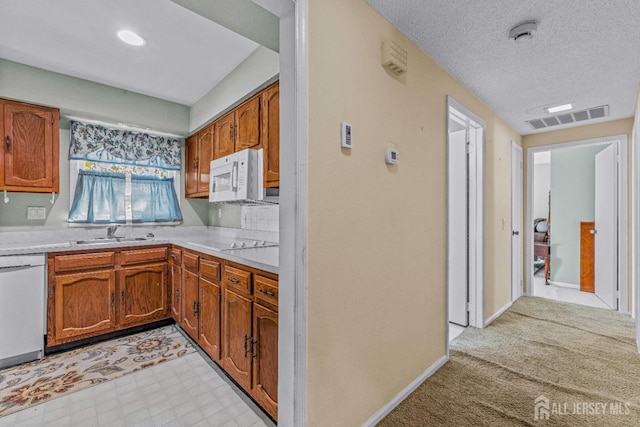 kitchen with light floors, light countertops, visible vents, a sink, and white appliances