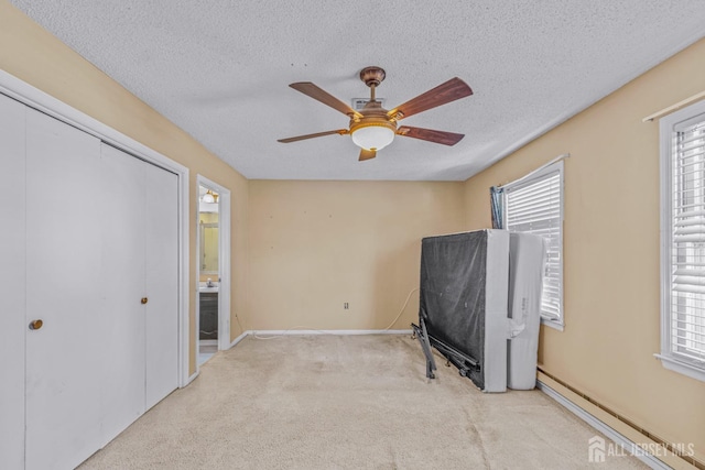 carpeted bedroom featuring multiple windows, ceiling fan, a textured ceiling, and a baseboard heating unit