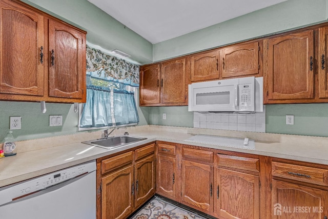 kitchen with white appliances, light countertops, and a sink