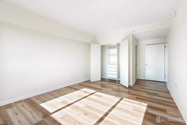 unfurnished bedroom featuring a closet, baseboards, and wood finished floors