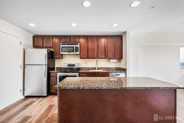 kitchen featuring a sink, tasteful backsplash, light wood-type flooring, and stainless steel appliances