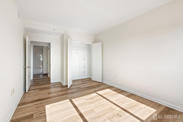 unfurnished bedroom with a closet, light wood-style flooring, and baseboards