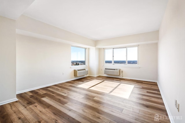 spare room featuring plenty of natural light, a wall mounted air conditioner, and wood finished floors