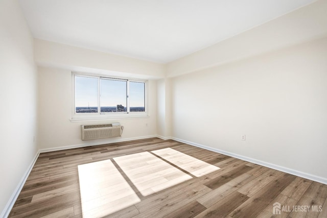 unfurnished room with baseboards, wood finished floors, and a wall mounted AC