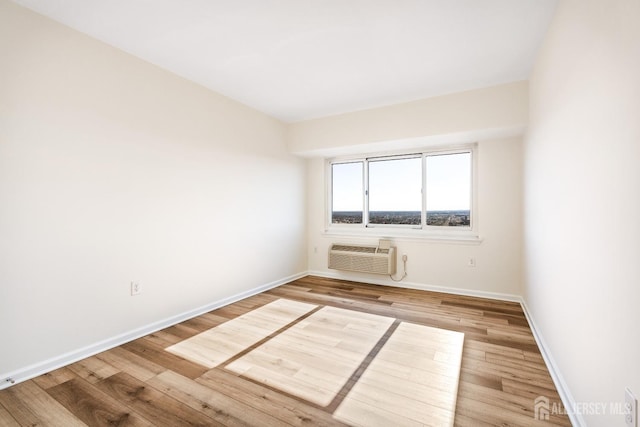 spare room with wood finished floors, baseboards, and a wall mounted AC