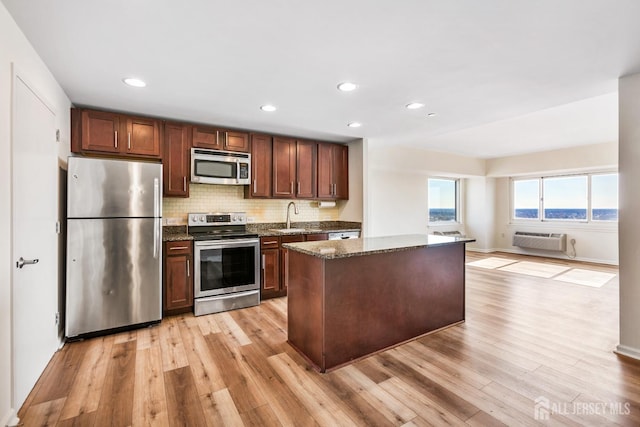 kitchen with a sink, light wood-style flooring, backsplash, and stainless steel appliances