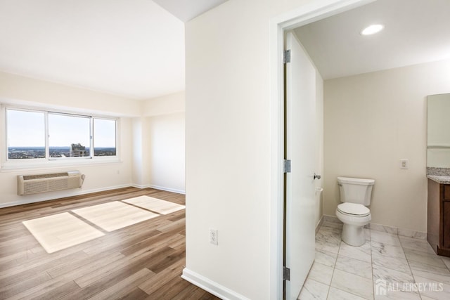 bathroom with vanity, a wall unit AC, baseboards, toilet, and marble finish floor