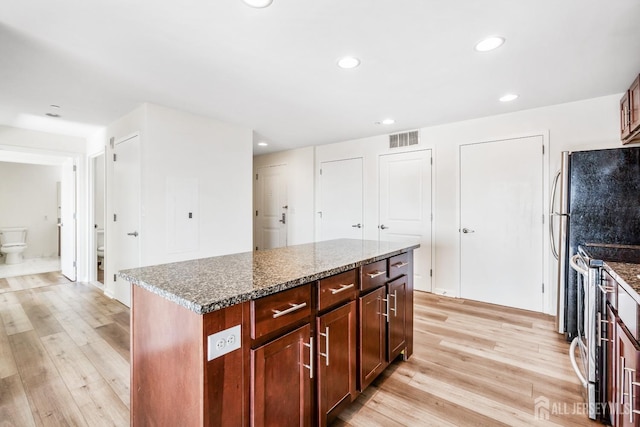 kitchen featuring visible vents, appliances with stainless steel finishes, dark stone counters, and light wood-style floors