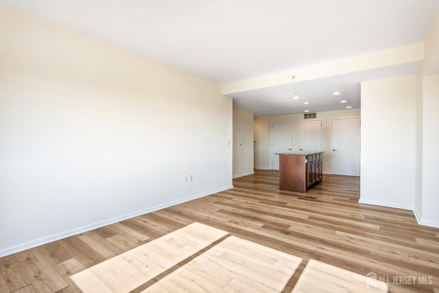 empty room with light wood finished floors, visible vents, recessed lighting, and baseboards