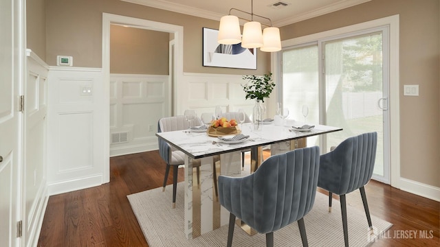 dining space with a decorative wall, dark wood finished floors, crown molding, and a wainscoted wall