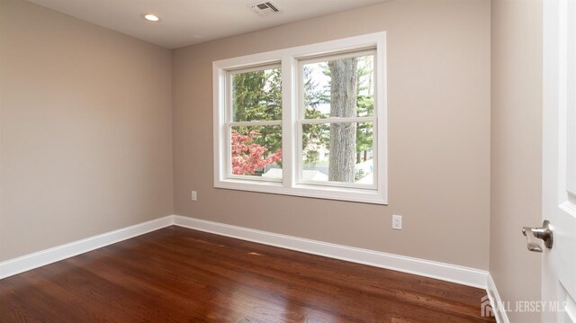 spare room with baseboards, dark wood finished floors, and recessed lighting