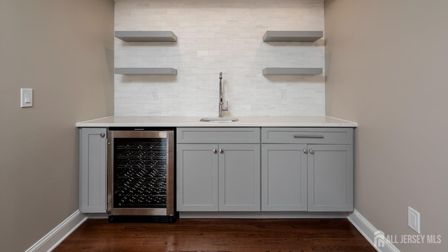indoor wet bar with wine cooler, decorative backsplash, baseboards, and dark wood-style floors