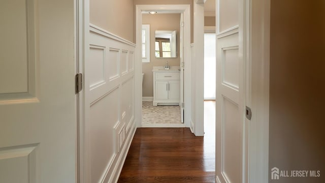 corridor featuring a sink and dark wood finished floors