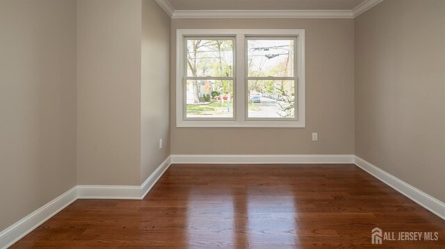 empty room with wood finished floors, ornamental molding, and baseboards