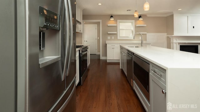 kitchen with appliances with stainless steel finishes, a sink, open shelves, white cabinets, and light countertops
